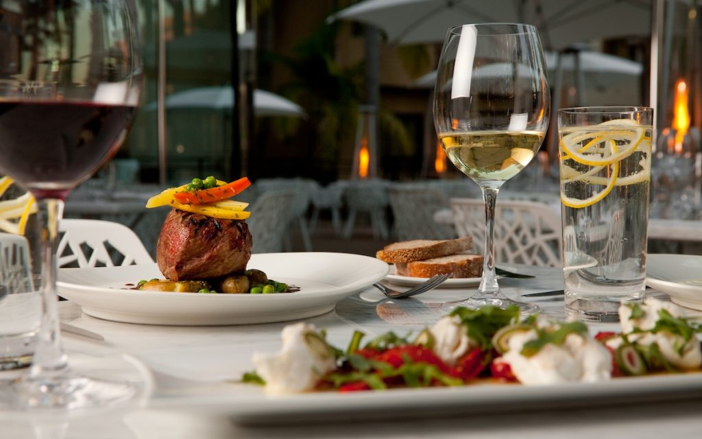 Table with steak, wine, and salad at Silver Trumpet Restaurant and Bar