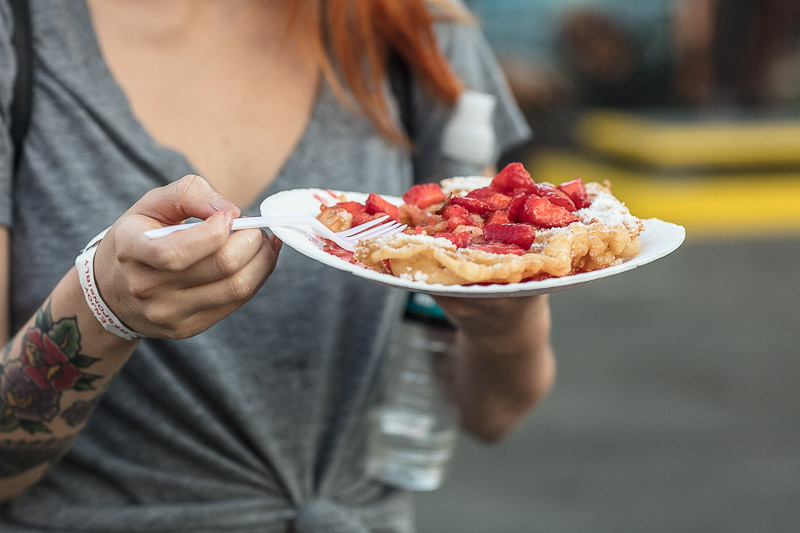 Woman holding funnel cake at the OC Fair. 